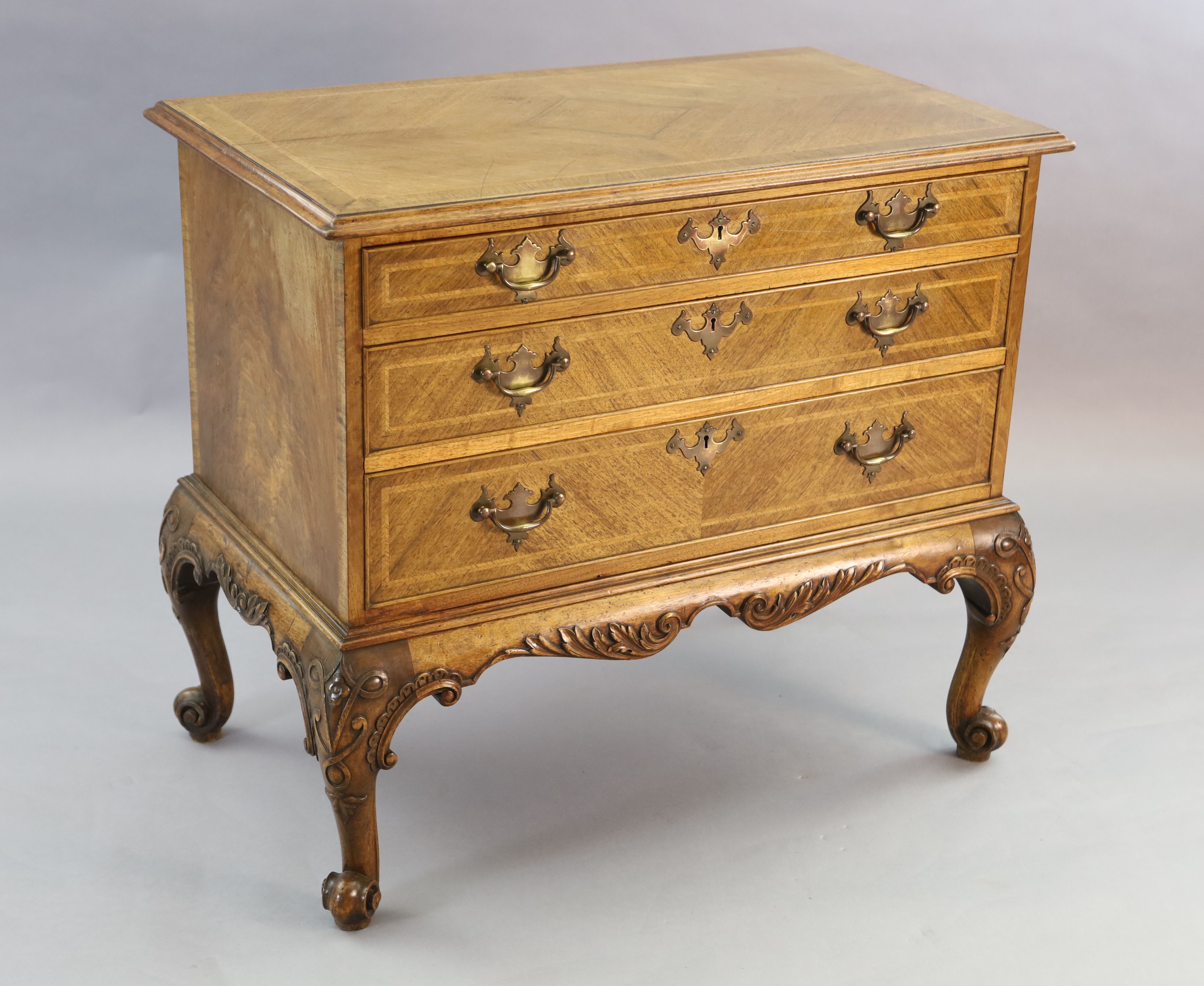 A Georgian style crossbanded walnut chest of three graduated long drawers, W.3ft 1in. D.1ft 10in. H.2ft 8in.